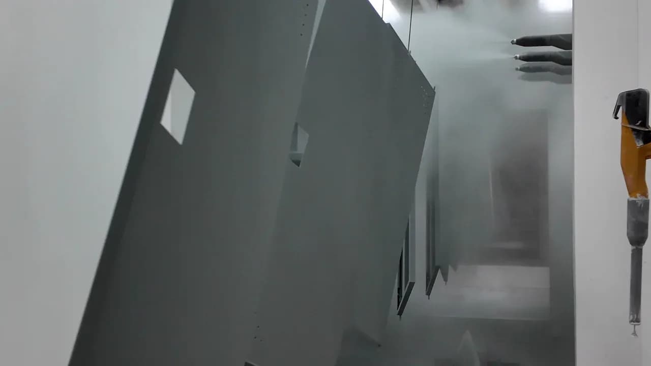 Dark gray metal cabinet panels moving between opposing spray guns in Yuzhen's powder-coating booth