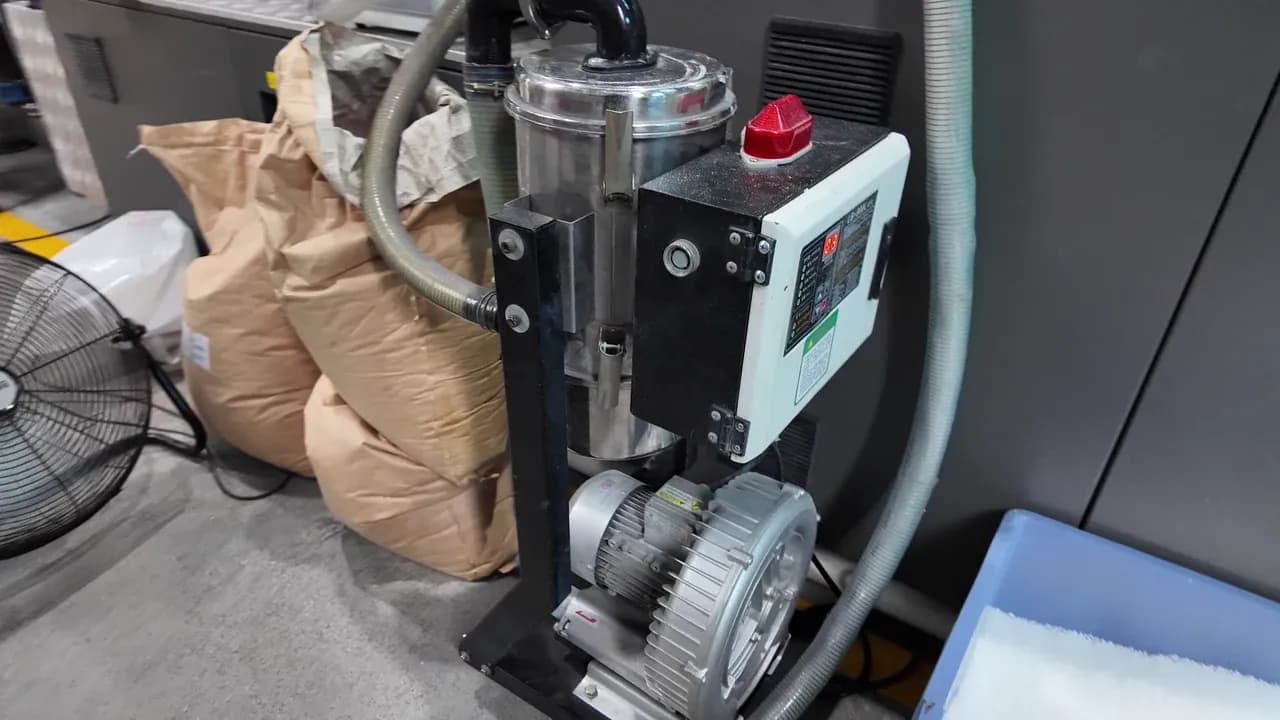 Système d'alimentation de matière pour injection Yuzhen Furniture Chargeur de matière au pied de la machine et granulés plastiques blancs dans l'atelier de moulage par injection de Yuzhen Furniture