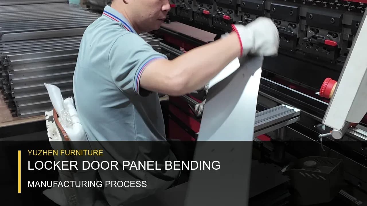 Processus de pliage des panneaux de porte métallique Yuzhen Furniture Opérateur soulevant un panneau de porte de casier métallique formé à côté d'une presse plieuse dans l'usine de Yuzhen Furniture