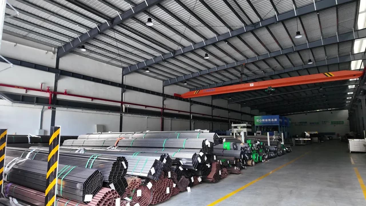 Stockage matières premières mobilier scolaire Yuzhen Furniture Faisceaux étiquetés de tubes métalliques stockés le long d'une allée balisée dans l'usine de mobilier scolaire de Yuzhen Furniture